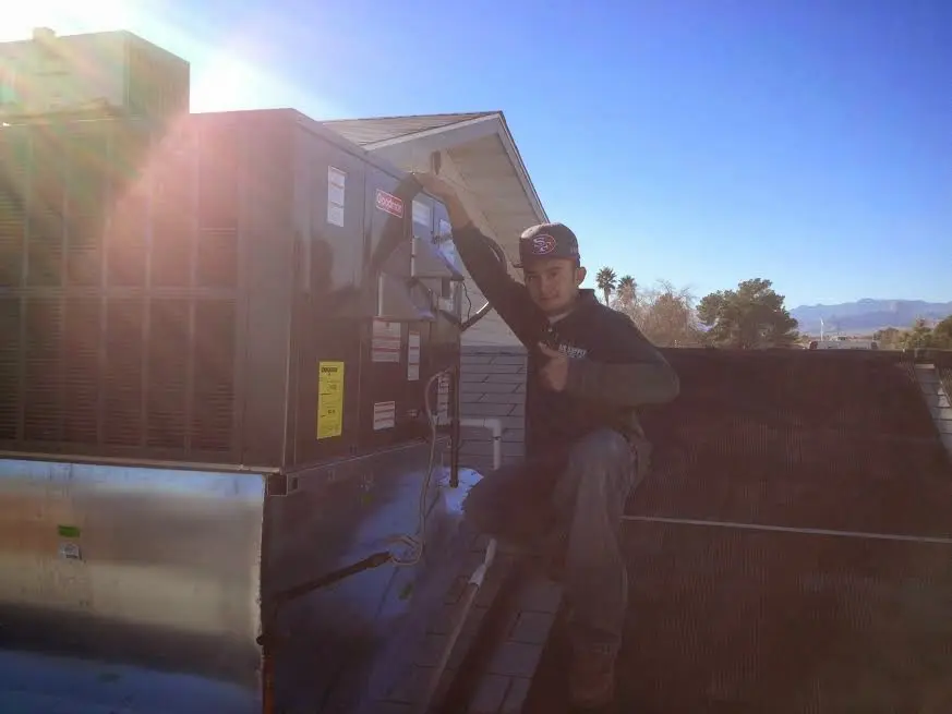 HVAC technician performing AC Tune-Up on a rooftop unit in Dania Beach