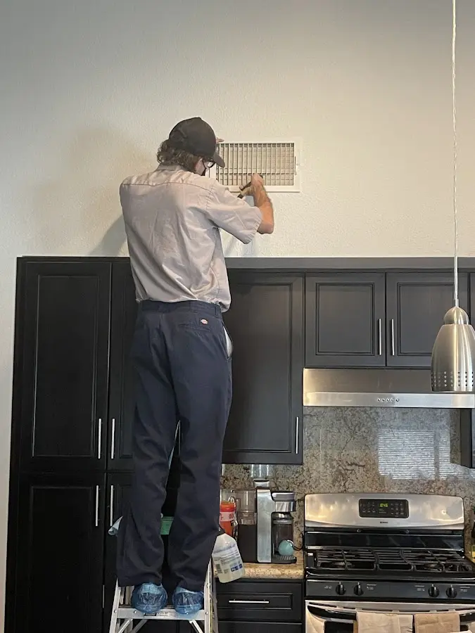 Technician inspecting an air vent during HVAC service in Dania Beach